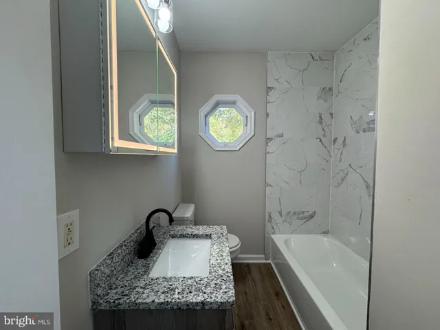 a bathroom with a granite countertop toilet a sink and a mirror