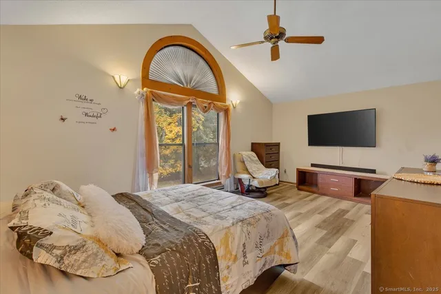 a bedroom with bed a flat tv screen and a chandelier