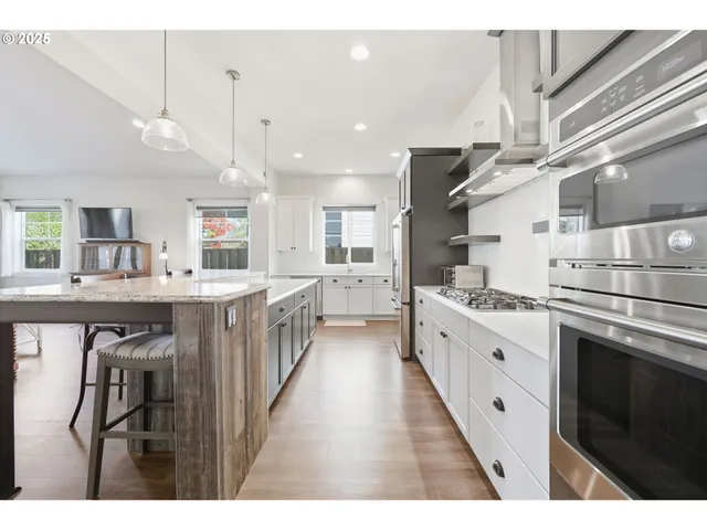 a large kitchen with stainless steel appliances kitchen island granite countertop a stove a sink dishwasher and a refrigerator