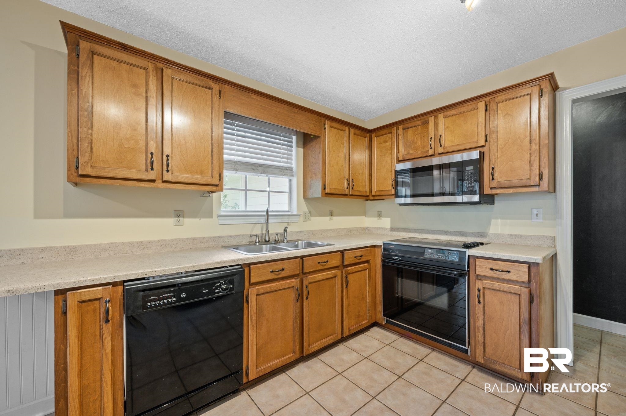 100 Montclair Loop Daphne, AL 36526 - Photo 17 of 39 Kitchen featuring sink, black appliances, light tile patterned flooring, and a textured ceiling