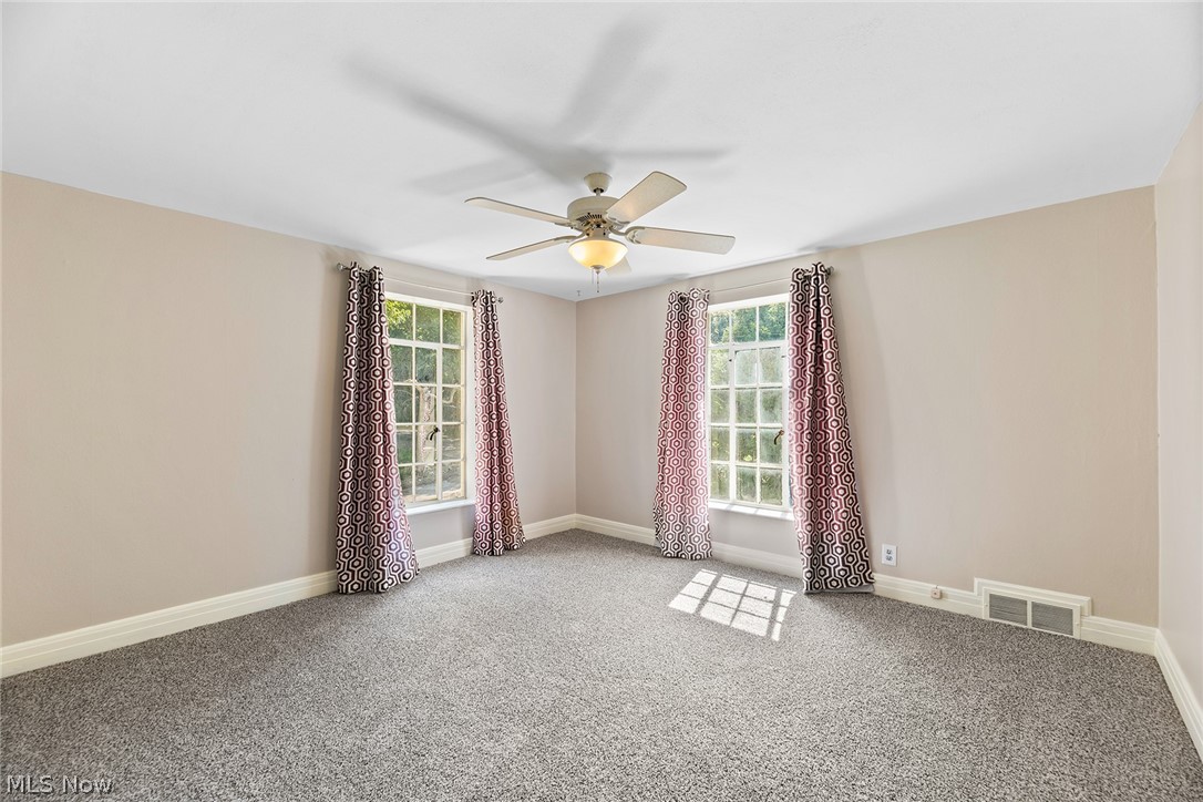1375 North Revere Road Akron, OH 44333 - Photo 32 of 50 Neutral wall tones, gray carpeting, dual windows, and a ceiling fan with integrated lighting