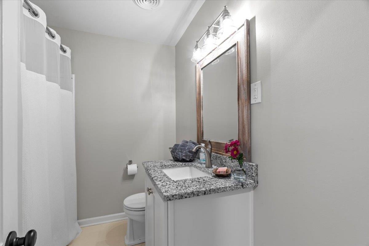 4491 Garnett Road Memphis, TN 38117 - Photo 21 of 32 Bathroom featuring a white vanity with a granite-style countertop, undermount sink, and a framed mirror with a four-light fixture