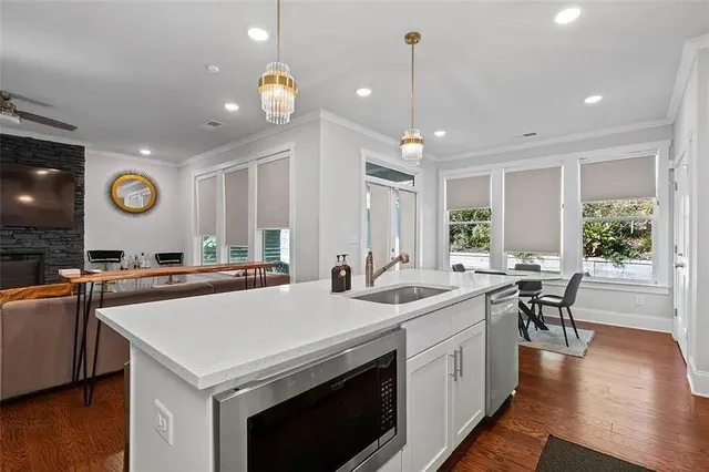 a kitchen with stainless steel appliances a sink a stove a microwave a center island and cabinets