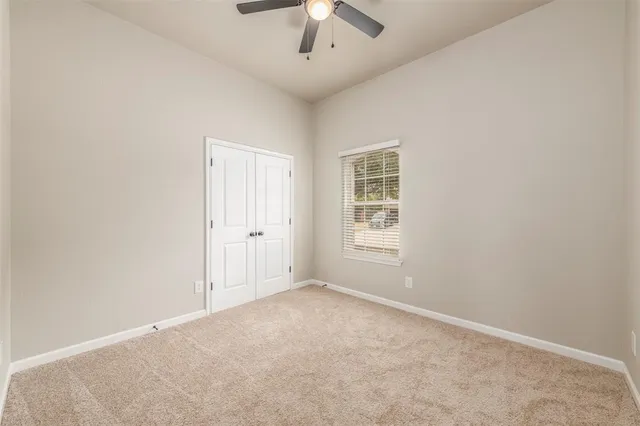 an empty room with a chandelier fan and windows