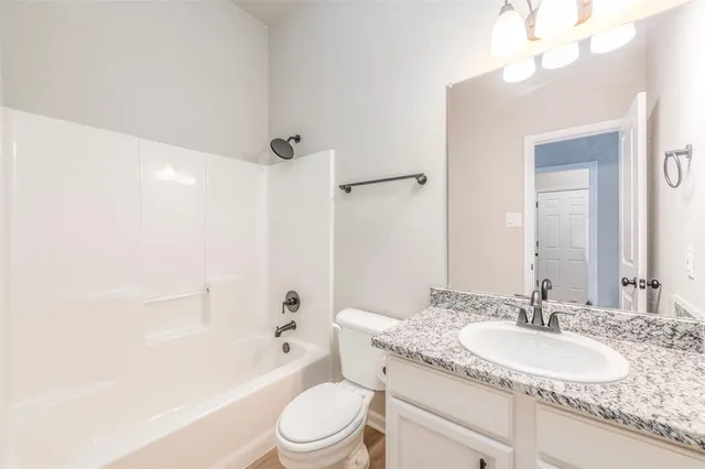 a bathroom with a granite countertop sink a toilet and shower