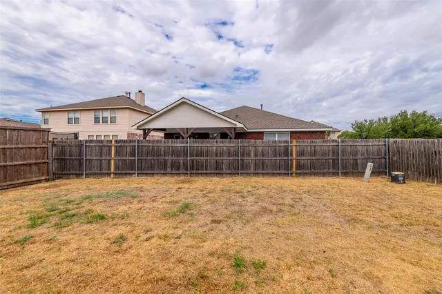 a view of a house with a yard and wooden fence