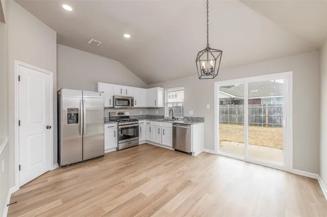 a large kitchen with a center island wooden floor stainless steel appliances and cabinets
