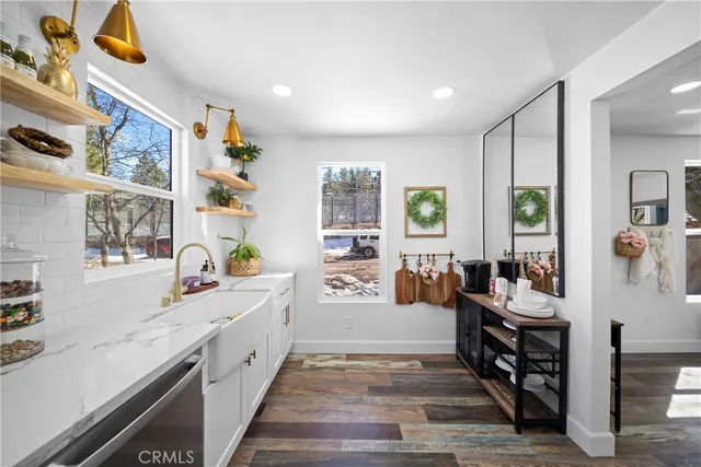 a large white kitchen with stainless steel appliances granite countertop a lot of counter space and a wooden floor