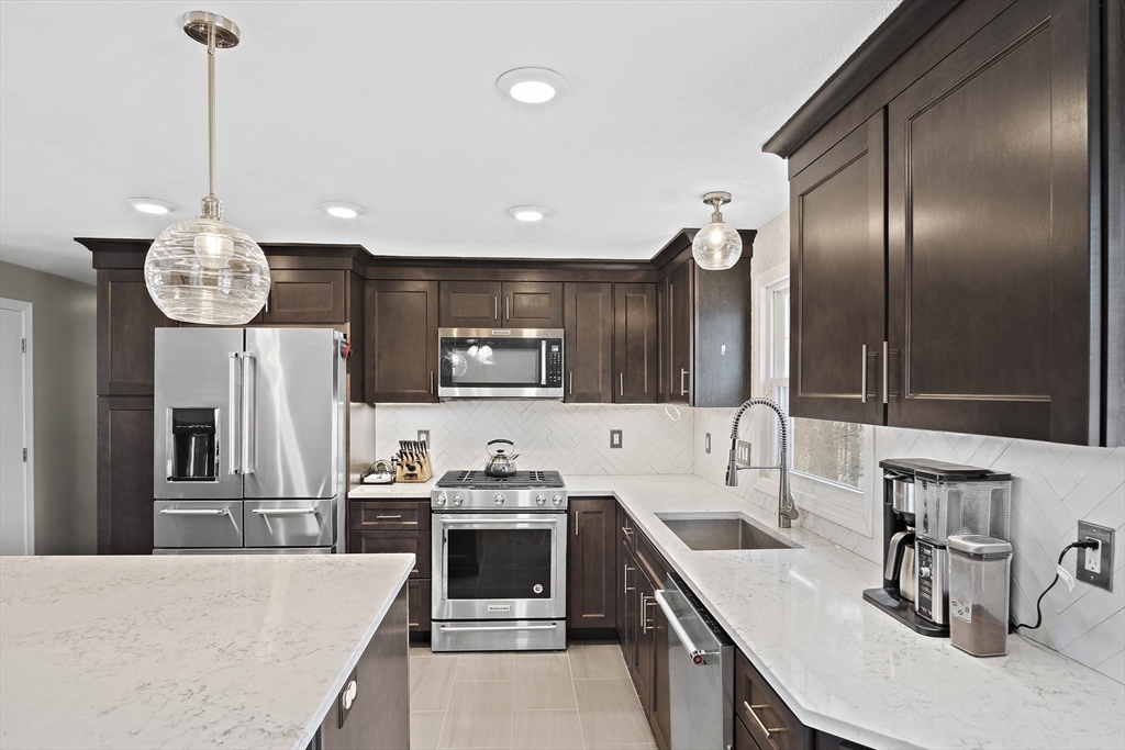 29 Dix Rd Extension Woburn, MA 01801 - Photo 8 of 40 a kitchen with stainless steel appliances kitchen island granite countertop a sink a stove and a wooden floors