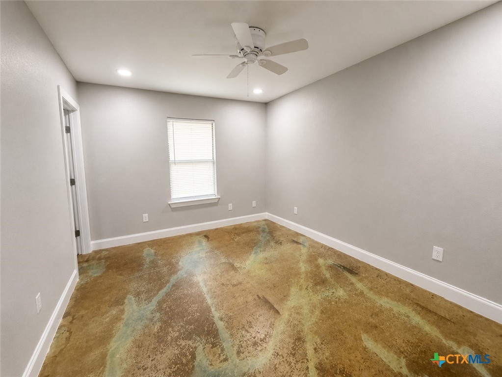661 West Austin Street, Unit Q Luling, TX 78648 - Photo 4 of 9 an empty room with a chandelier fan and windows