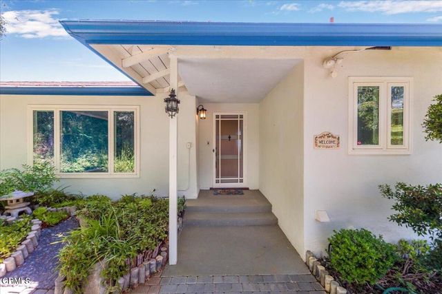 a living room with stainless steel appliances furniture a rug and a window