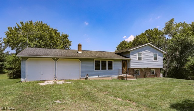 View of front facade with a chimney, a garage, and a front yard