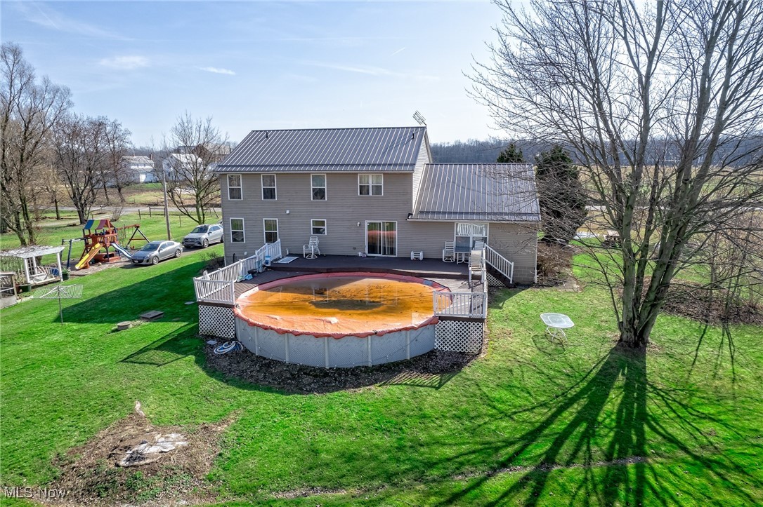 12181 Williams Road Homerville, OH 44235 - Photo 39 of 49 Back of house with a pool side deck, a playground, and a lawn