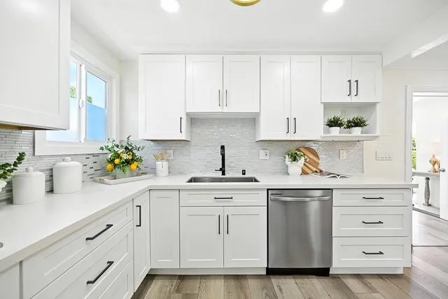 a kitchen with white cabinets white appliances and sink