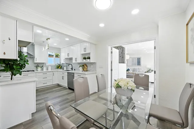 a living room with white cabinets and couches with kitchen view