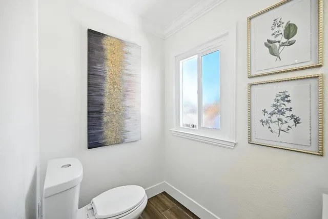a white toilet sitting next to a window in a bathroom