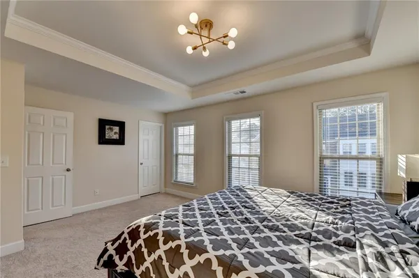 a large bed sitting in a bedroom next to a window and a chandelier