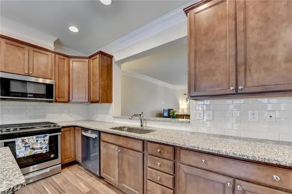 a kitchen with granite countertop cabinets stainless steel appliances a sink and wooden floor