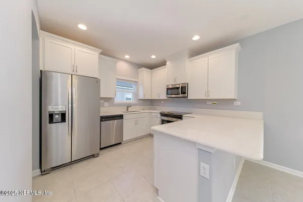a kitchen with a refrigerator a sink and white cabinets