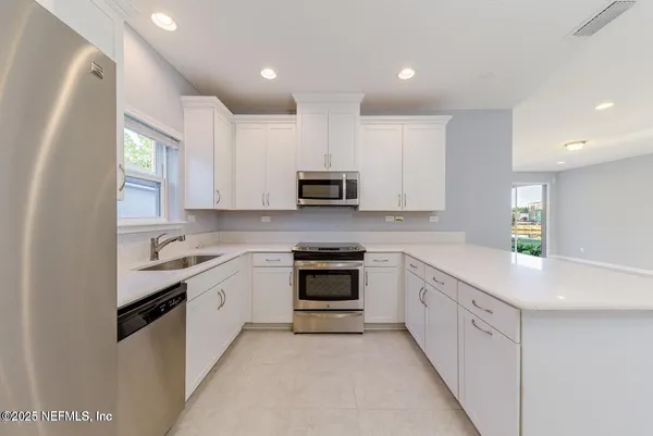 a kitchen with granite countertop white cabinets and stainless steel appliances