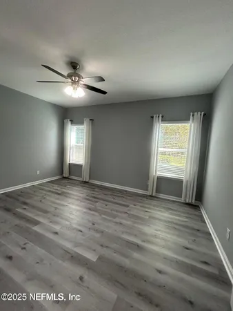 a view of an empty room with window and wooden floor