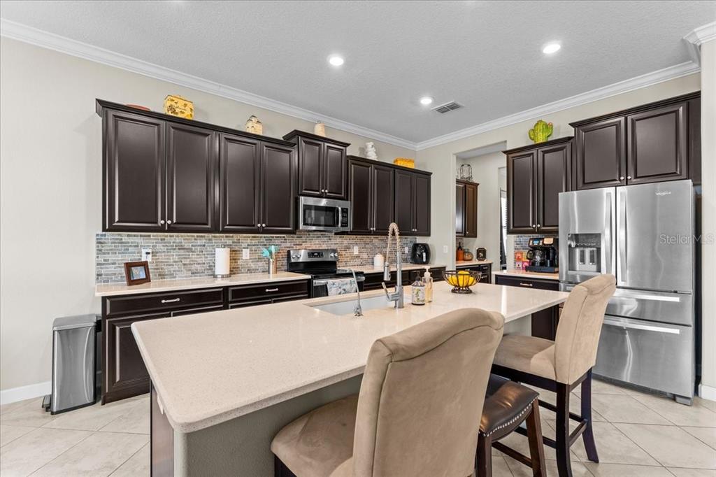 13443 White Sapphire Road Riverview, FL 33579 - Photo 7 of 47 a kitchen with stainless steel appliances granite countertop a refrigerator a stove top oven a sink dishwasher and wooden cabinets