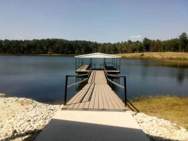 a view of wooden deck and lake with trees in the background