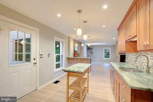a kitchen with kitchen island granite countertop a sink a counter space appliances and cabinets