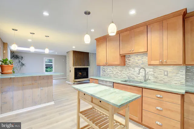 a kitchen with stainless steel appliances granite countertop a refrigerator a sink dishwasher a stove and white cabinets with wooden floor