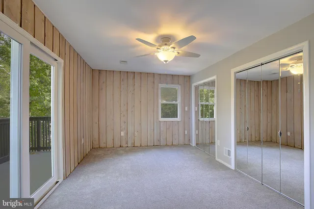 an empty room with windows and ceiling fan