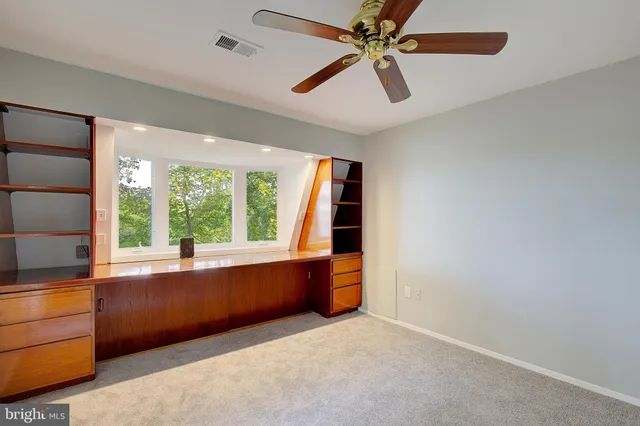 an empty room with closet and a ceiling fan