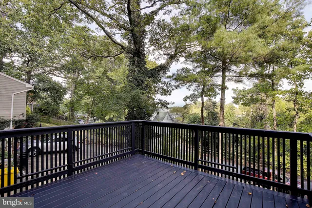 a view of a white house next to a yard with plants and large trees