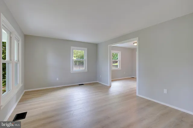 a view of an empty room with window and wooden floor