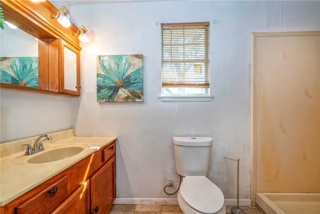 a bathroom with a granite countertop toilet sink and mirror