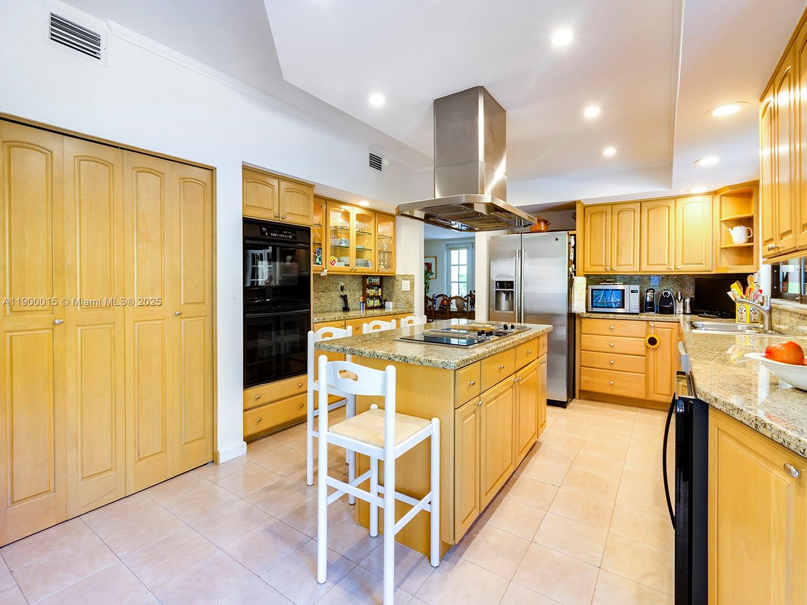 7950 Old Cutler Road Coral Gables, FL 33143 - Photo 8 of 30 a kitchen with stainless steel appliances kitchen island granite countertop a refrigerator a stove top oven and white cabinets