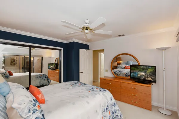 a bedroom with a bed a dresser and flat screen tv