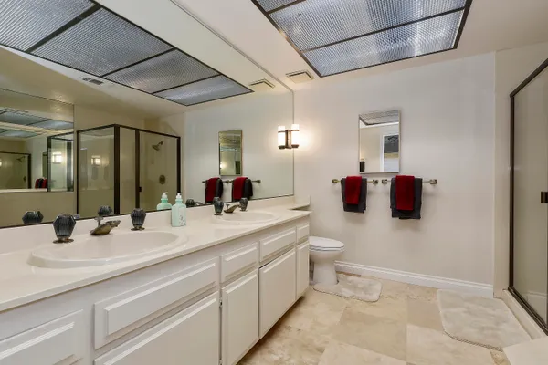 a bathroom with a double vanity sink toilet mirror and shower
