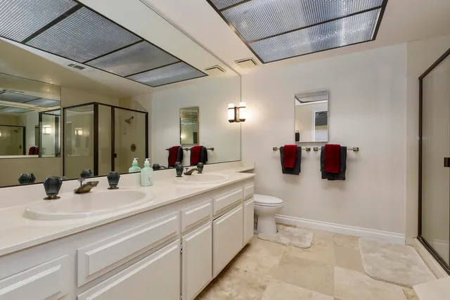 a bathroom with a double vanity sink toilet mirror and shower