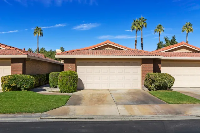 a front view of a house with a garden and plants