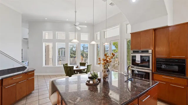 a kitchen with stainless steel appliances granite countertop a stove a refrigerator a kitchen island a dining table and chairs with wooden floor