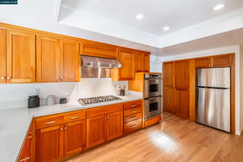 a kitchen with stainless steel appliances granite countertop a refrigerator a sink dishwasher and wooden cabinets with wooden floor