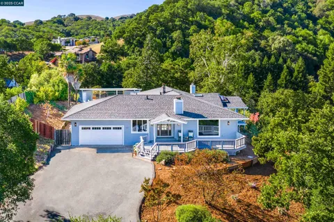 a view of a house with a big yard plants and large trees