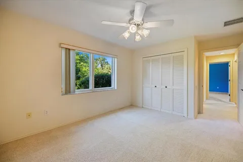 an empty room with window and ceiling fan