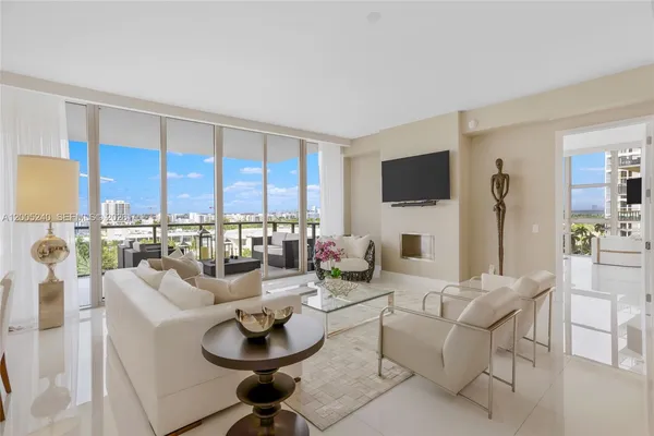 a living room with furniture a flat screen tv and a floor to ceiling window
