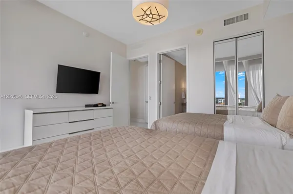 a bedroom with two large bed and a chandelier