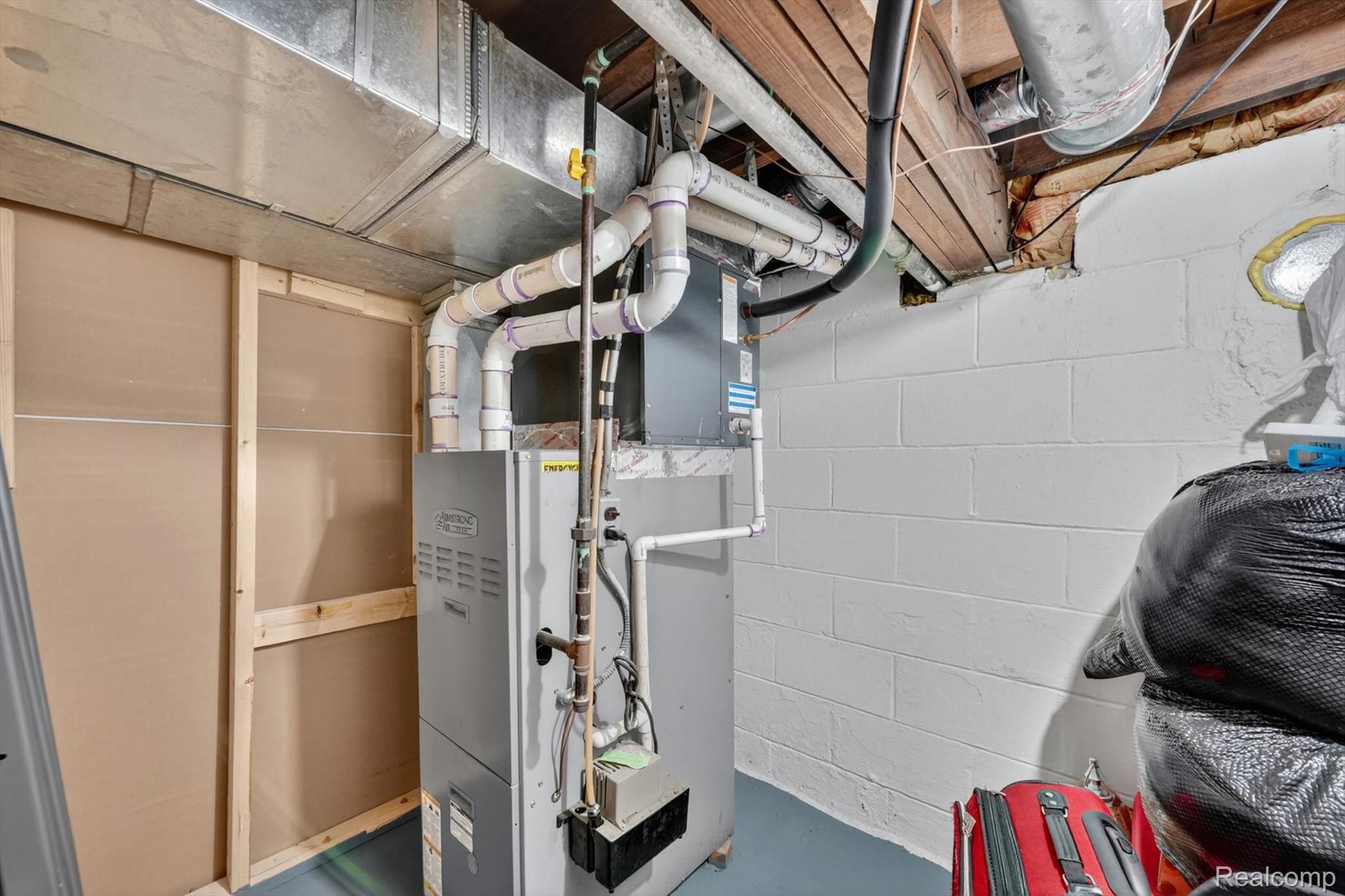2861 John R Road Rochester, MI 48307 - Photo 37 of 54 Utility room featuring a furnace system with associated ductwork and PVC piping, painted cinder block walls, exposed wood ceiling joists, and a partial wood-framed wall