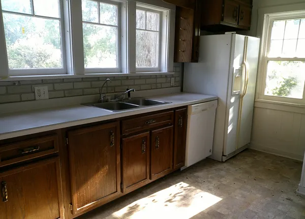 a kitchen with stainless steel appliances granite countertop a refrigerator a sink a stove a washer and dryer next to a window