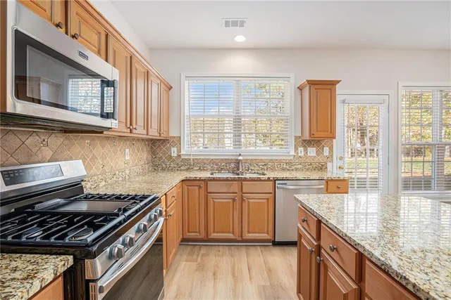 a kitchen with stainless steel appliances granite countertop a stove a sink and a white cabinets