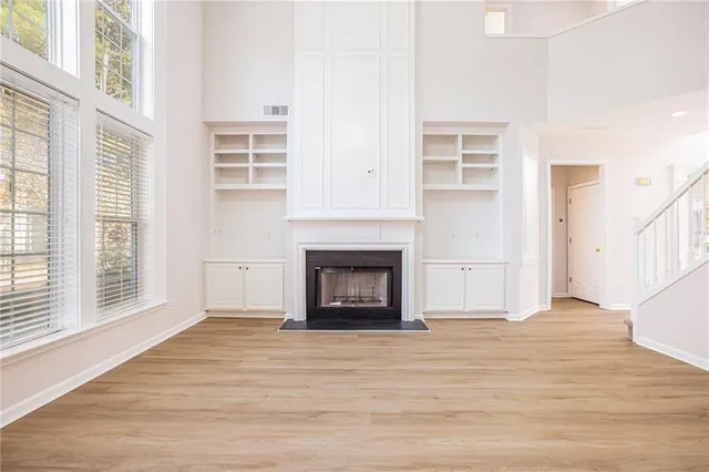 a view of an empty room with wooden floor fireplace and a window