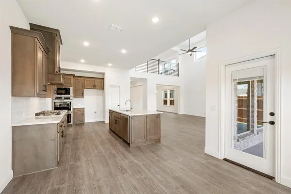 a view of kitchen with kitchen island wooden floors and stainless steel appliances